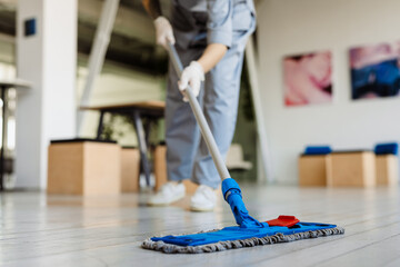 White cleaning woman in gloves washing floor with mop