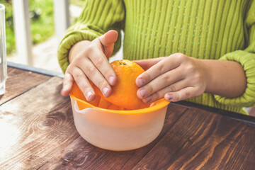 the girl child makes freshly squeezed orange juice on a manual juicer