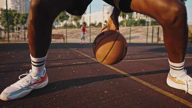 Close-up of a young black basketball player dribbling the ball across the field. Male athlete training on the basketball court - Powered by Adobe