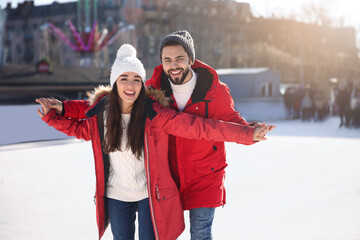 Lovely couple spending time together at outdoor ice skating rink - obrazy, fototapety, plakaty