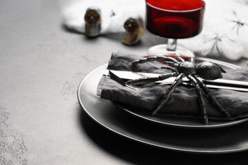 Festive Halloween table setting with red glass, black spider and horror decoration. Close up.