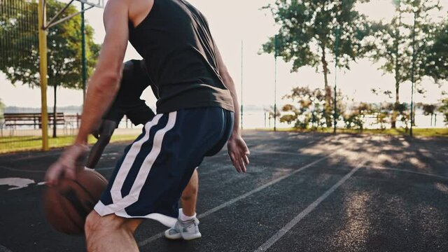 Caucasian basketball player dribbles the ball against an African American and makes an effective pass. Three-point shot