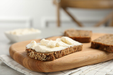 Fototapeta na wymiar Bread with cream cheese on wooden table, closeup