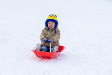 Boy sliding down the hill on saucer sleds outdoors, winter day, ride down the hills, winter games and fun