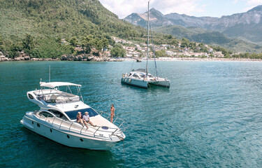 Aerial view of a luxury motor yacht and catamaran sailing the sea and beautiful Mediterranean...