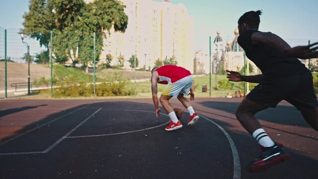 Close-up of a basketball fight and dribbling. A young athlete holds the ball and pushes the opponent, fouls and scores a goal