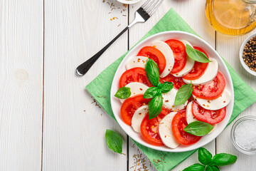 Caprese salad of tomatoes, mozzarella cheese, basil and olive oil on a white background.