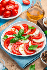 Caprese salad with tomatoes, mozzarella and basil on a blue background.