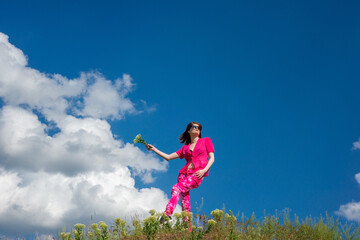 young beautiful girl in pink on a background of clouds in the summer blue sky