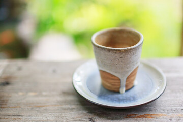 cup of coffee with milk flow style on wooden table and blur green background