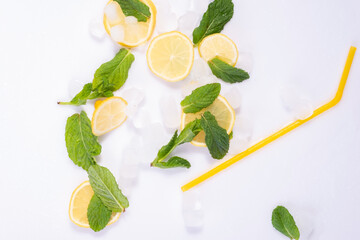 spilled glass of refreshing summer cocktail with ice, lemon and mint on white background