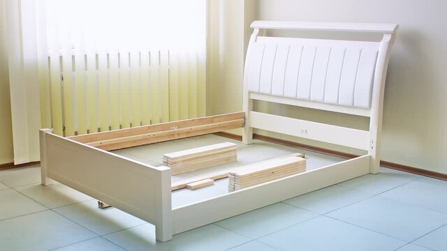 installation of the frame of an orthopedic wooden double bed with a soft leather back in white