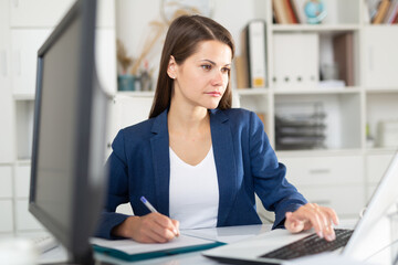 Smiling woman working with papers and laptop in office