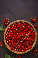 Fresh red currant in wooden bowl on dark table