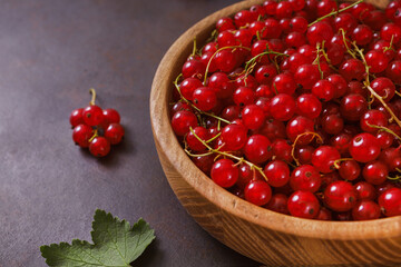Fresh red currant in wooden bowl on dark table