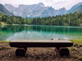 Bench on the shore of a mountain lake with a beautiful mountain landscape in the afternoon. - Powered by Adobe