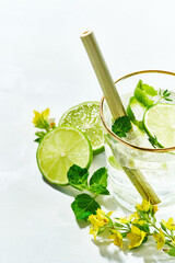 Fresh drinks with lime and mint garnishing with fresh flowers, cold summer lemonade on white background.copy space. Modern minimalism concept.