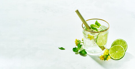 Fresh drinks with lime and mint garnishing with fresh flowers, cold summer lemonade on white background.copy space. Modern minimalism concept.