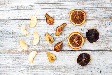 Pattern of a pile of dried pears citrus and apples in slices on a white wooden background. Dried fruit chips.