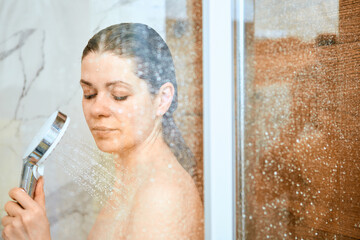 Woman brunette with long hair take a shower.