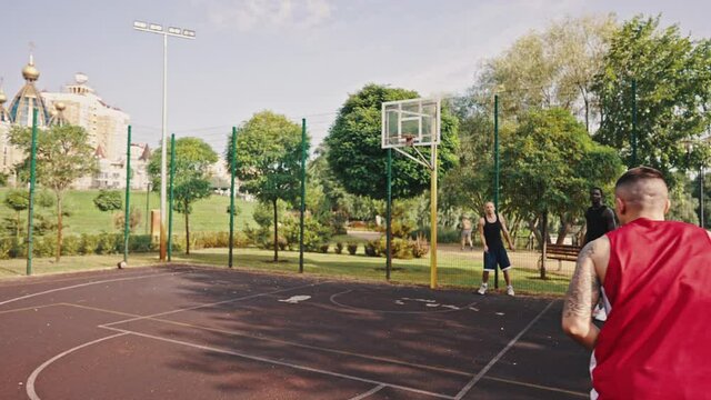 Three-point shot. Young basketball player playing with friends on the outdoor basketball court