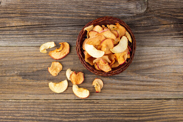 Obraz na płótnie Canvas A pile of dried slices of apples in wicker basket on wooden background. Dried fruit chips. Healthy food
