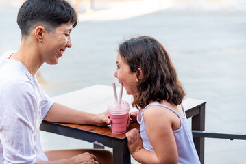 Mother and daughter having fun drinking milkshake