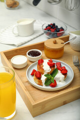 Fototapeta na wymiar Delicious cottage cheese pancakes with fresh strawberries sour cream and mint served on white countertop