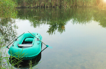 Rubber inflatable boat with oars in the lake on a summer morning in the wild. Morning fishing....