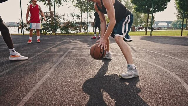 Close-up basketball dribbling. Caucasian and African American guys are vying for the ball. Outdoor court game