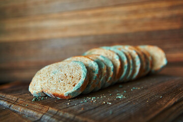 Moldy spoiled bread on a wooden background. Improper storage of food. - obrazy, fototapety, plakaty