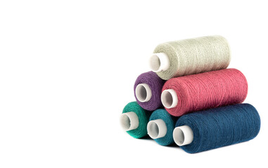 Pyramid from spools of threads of different colors on a white background.