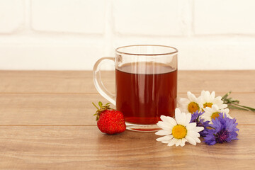 Glass cup of tea with white chamomile flowers