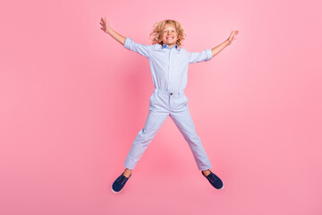 Fototapeta na wymiar Photo of adorable funky school boy wear blue shirt jumping like star smiling isolated pink color background