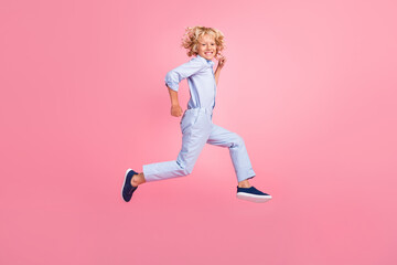 Fototapeta na wymiar Full size profile side photo of smiling boy running fast speed in air freedom summer isolated on pink color background