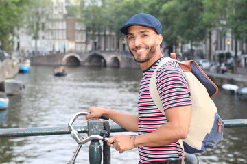 Young mixed race man enjoying a European cityscape view with a river 