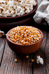 grains of popcorn on a dark background, in a wooden bowl, on the background ready popcorn, rustic