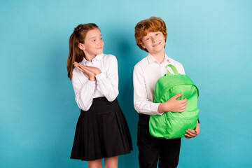Portrait of two attractive cheerful friends holding bag preparing to lesson isolated over bright blue color background