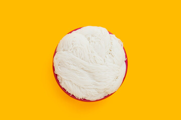 Thai rice noodle in red plastic basket on yellow background.