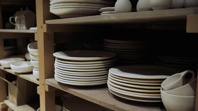White ceramic plates are on the shelves in the production shop and waiting for painting. Sale of white ceramic plates without final coating. High quality 4k footage