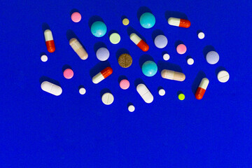 A lot of multi-colored pills on blue background, as a concept of medical treatment with a prescription. Painkillers and antibiotics variation, allergy on medicine.
