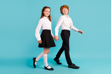 Fototapeta premium Full length body size profile side view of two nice cheerful kids going holding hands lesson isolated over bright blue color background