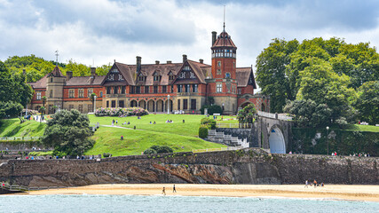 Fototapeta premium San Sebastian, Spain - 2 August 2021: Miramar Palace and Ondaretta Beach from La Concha Bay