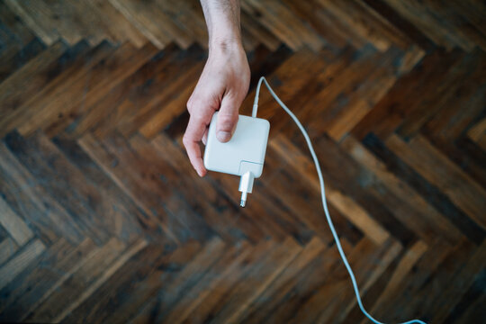 Closeup shot of a male hand holding a white charger over a parquette background