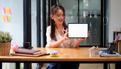 Cheerful businesswoman holding and showing digital tablet with blank screen.