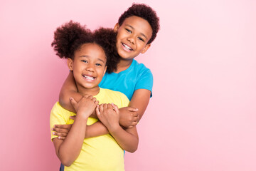 Portrait of two attractive cheerful kid friends hugging having fun isolated over pink pastel color...