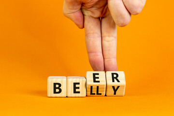 Beer belly symbol. Doctor turns wooden cubes with words 'beer belly'. Beautiful orange table, orange background, copy space. Medical, healthy lifestyle and beer belly concept.