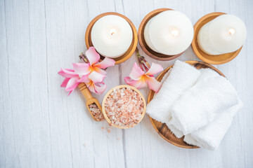 Natural relaxing spa composition on massage table in wellness center    with towels, flowers and salt, candle  on massage table in spa salon.