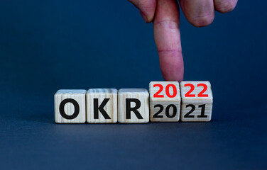 OKR, objectives and key results symbol. Businessman turns cubes with words 'OKR 2021' and 'OKR 2022' on beautiful grey background. Business, OKR 2022, objectives and key results concept. Copy space.