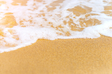 Sea wave foam breaking on the beach sand, travel and summer background with copy space